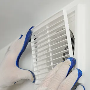 A person in white gloves and blue gloves cleaning a window.