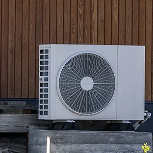 A white air conditioner sitting on top of a cement block.